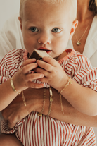 A tender moment featuring a baby and mum wearing matching gold bracelets — the Pink Darling and Posie — with heart charms, as the baby holds a velvet box.