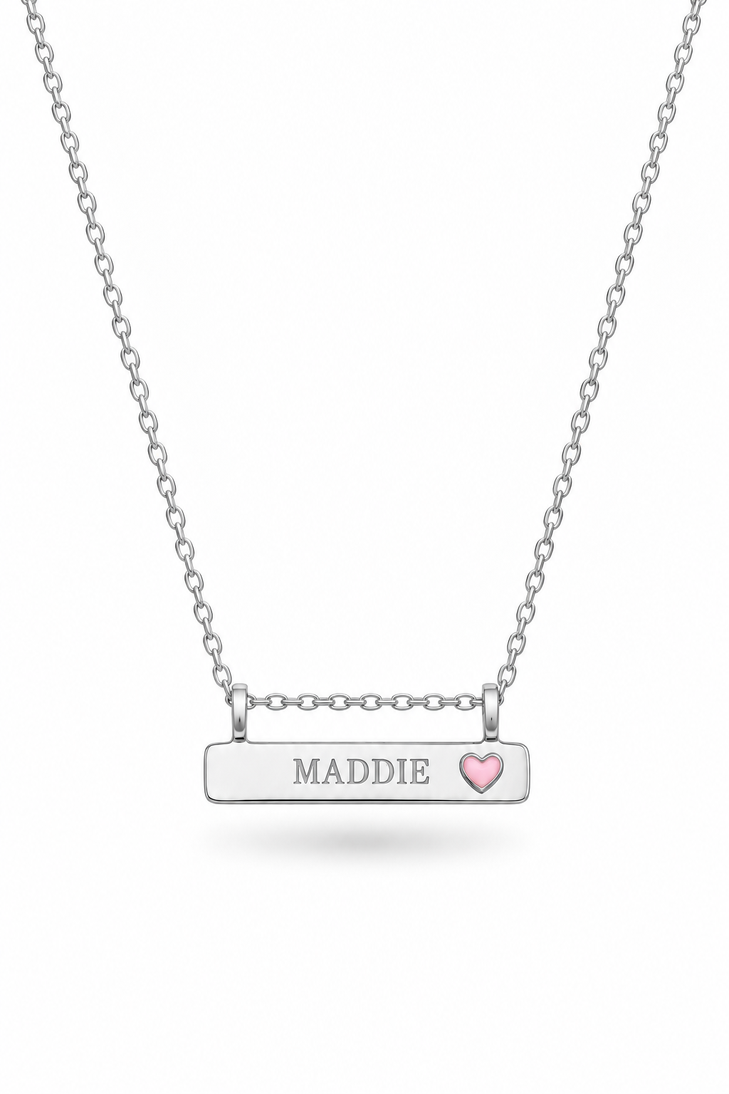A silver Bluebird persoanlised bar necklace with the name 'MADDIE' engraved on the bar and a small pink heart on the right side, suspended from a delicate silver chain against a white background.