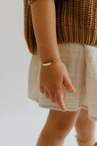 A young girl is wearing an engravable Darling Bracelet that is Rose Gold.  The Bluebird Bracelet can be personalised with complimentary engraving on the front and rear of the bar pendant.