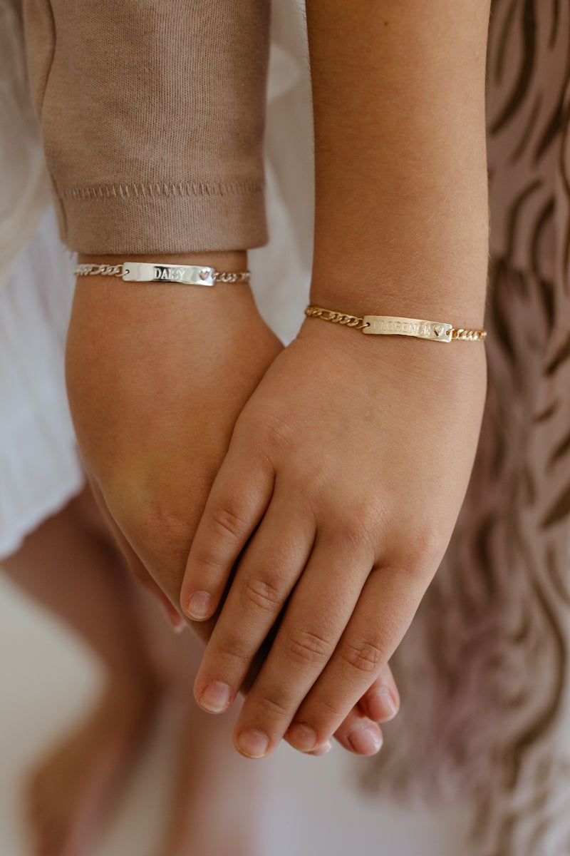 Matching Darling Friendship Bracelets are worn by two young girls.  The bracelet on the right is the Darling Bracelet in Gold Vermeil and it featured personalised engraving on the front of the ID Bracelet bar pendant.  