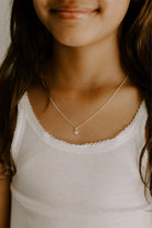 The Pink Petite Darling necklace with its soft pink heart pendant on a fine cable chain is worn by a 9 year old girl.