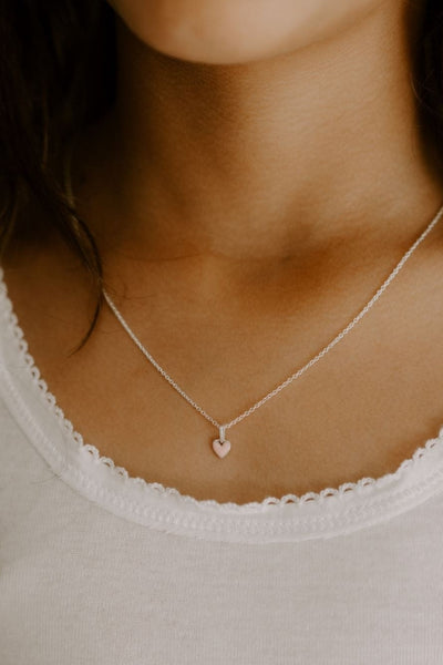 A young girl is wearing the Pink Petite Darling Necklace in sterling silver.  She is wearing the 35cm length and it sits beautifully above her shirt neckline.
