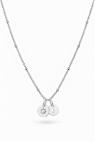 A silver beaded chain necklace with two small round pendant charms, one engraved with a sunburst and the other with the letter 'J', shown on a plain white background.