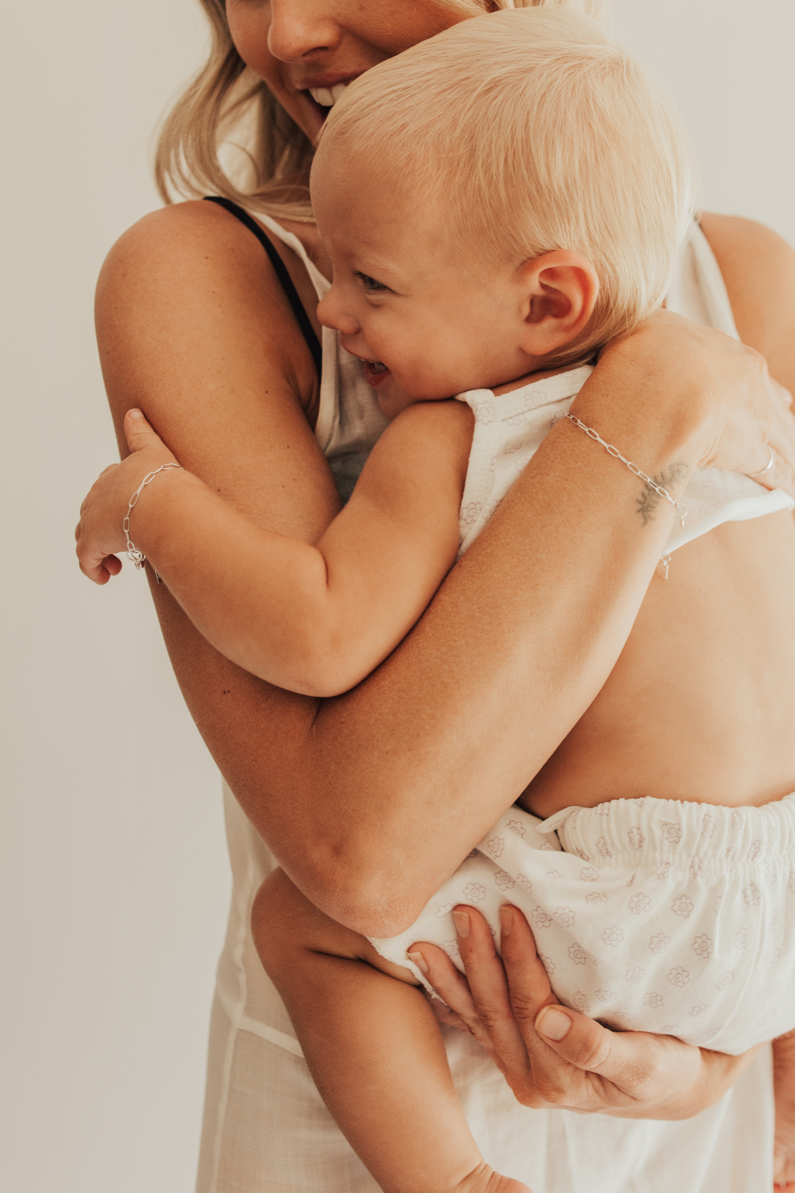 A warm image of a mum and baby wearing matching Posie Bracelets with heart charms by Bluebird Jewellery, captured in a moment of happiness and connection 