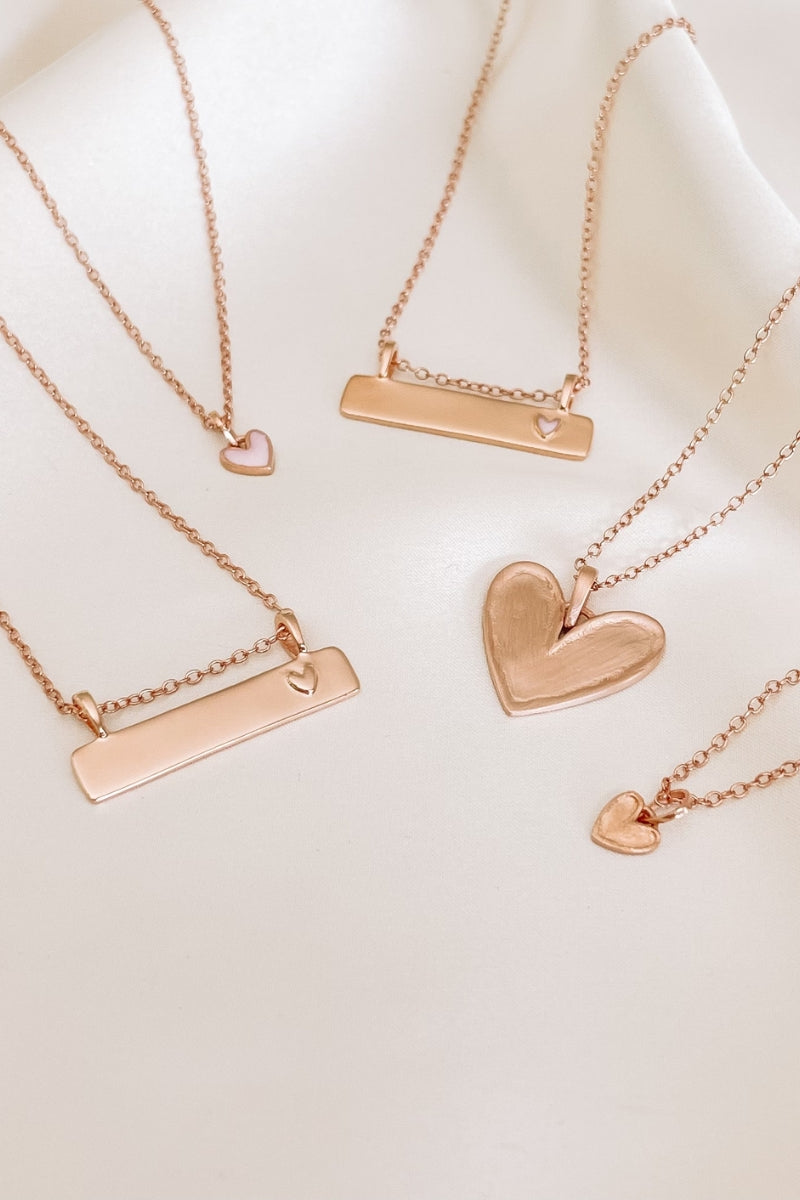 Engraved rose gold necklaces with heart and bar pendants, keepsake gifts designed to be treasured for a lifetime.