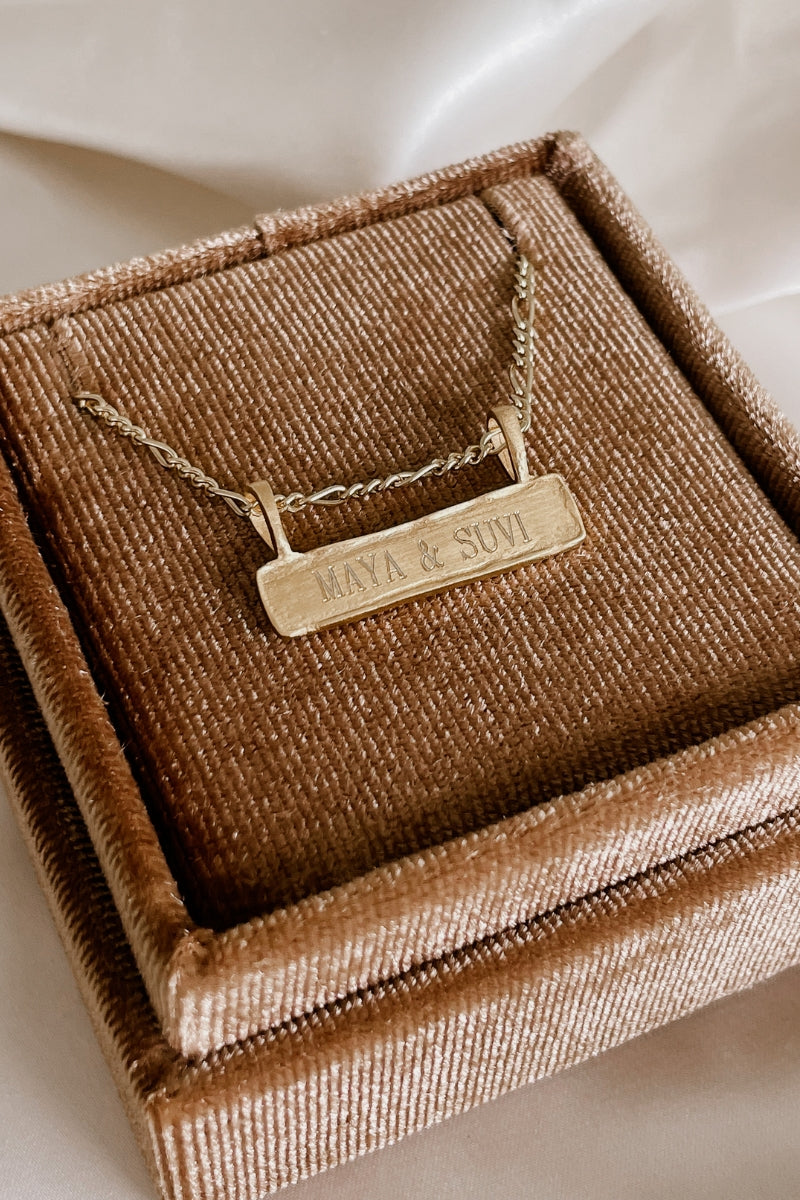 A close up look at the Signature Bar Necklace resting inside a velvet Bluebird Co gift box.