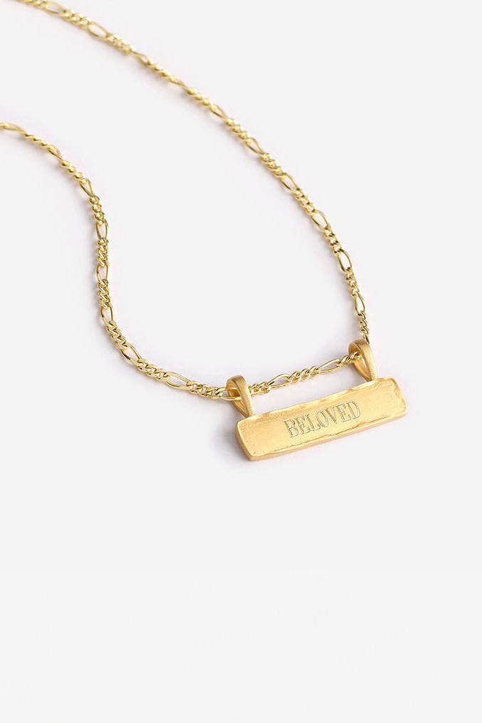 a Signature Bar Necklace with the word BELOVED engraved on the front of the bar pendant.  The necklace features a figaro necklace chain and a raised, textured edge on the bar pendant.