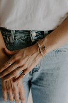 A close up of the Signature Bracelet in child size worn by an adult alongside the Loved Bracelet.