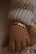 A baby is wearing a Baby sized Signature Bracelet with personalised engraving on it.