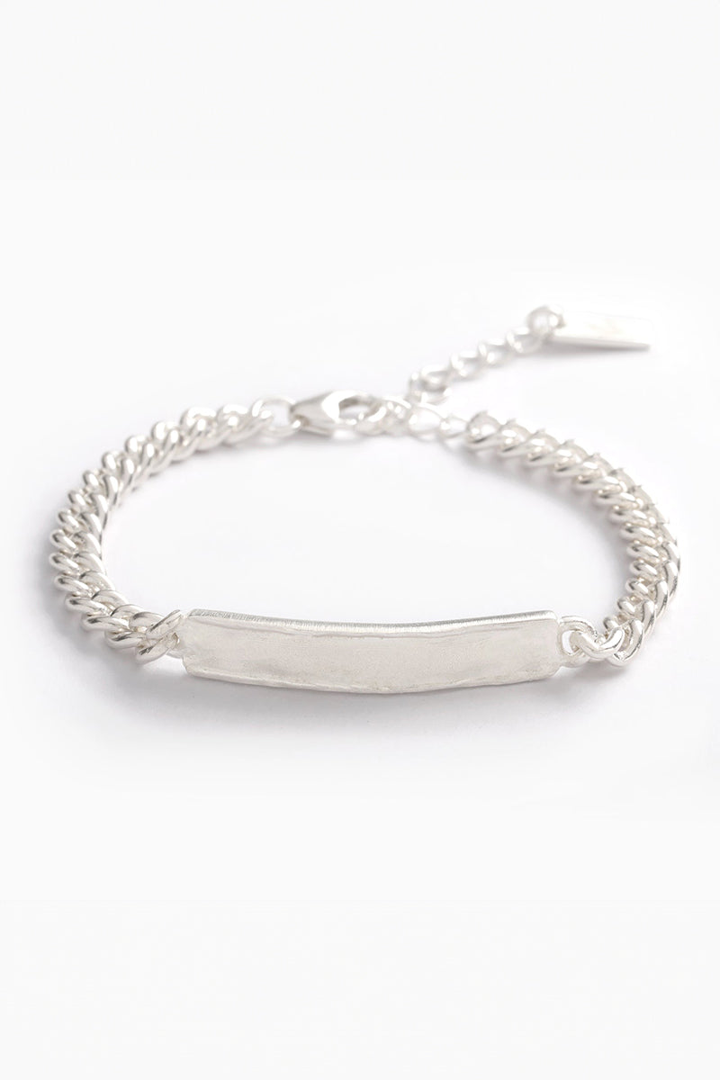 Close-up of silver signature bracelet with engraved plate and adjustable chain on white background