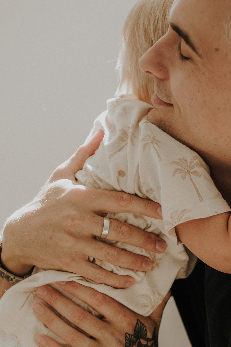 A dad is hugging his son after receiving a signature ring with engraving inside it