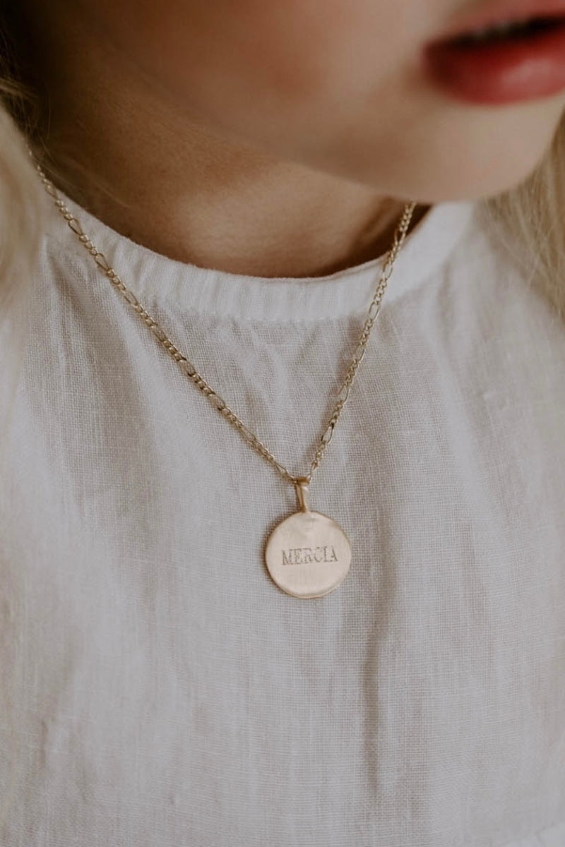 A young girl is wearing the child length Signature Necklace with her name engraved on the front of the personalised pendant.