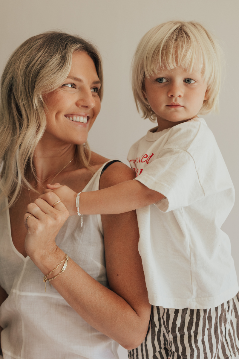 A mother is smiling at her son who is wearing a personalised signature bracelet with personalised engraving on it.  This Bluebird Bracelet is part of the Signature Collection and is made from solid sterling silver.