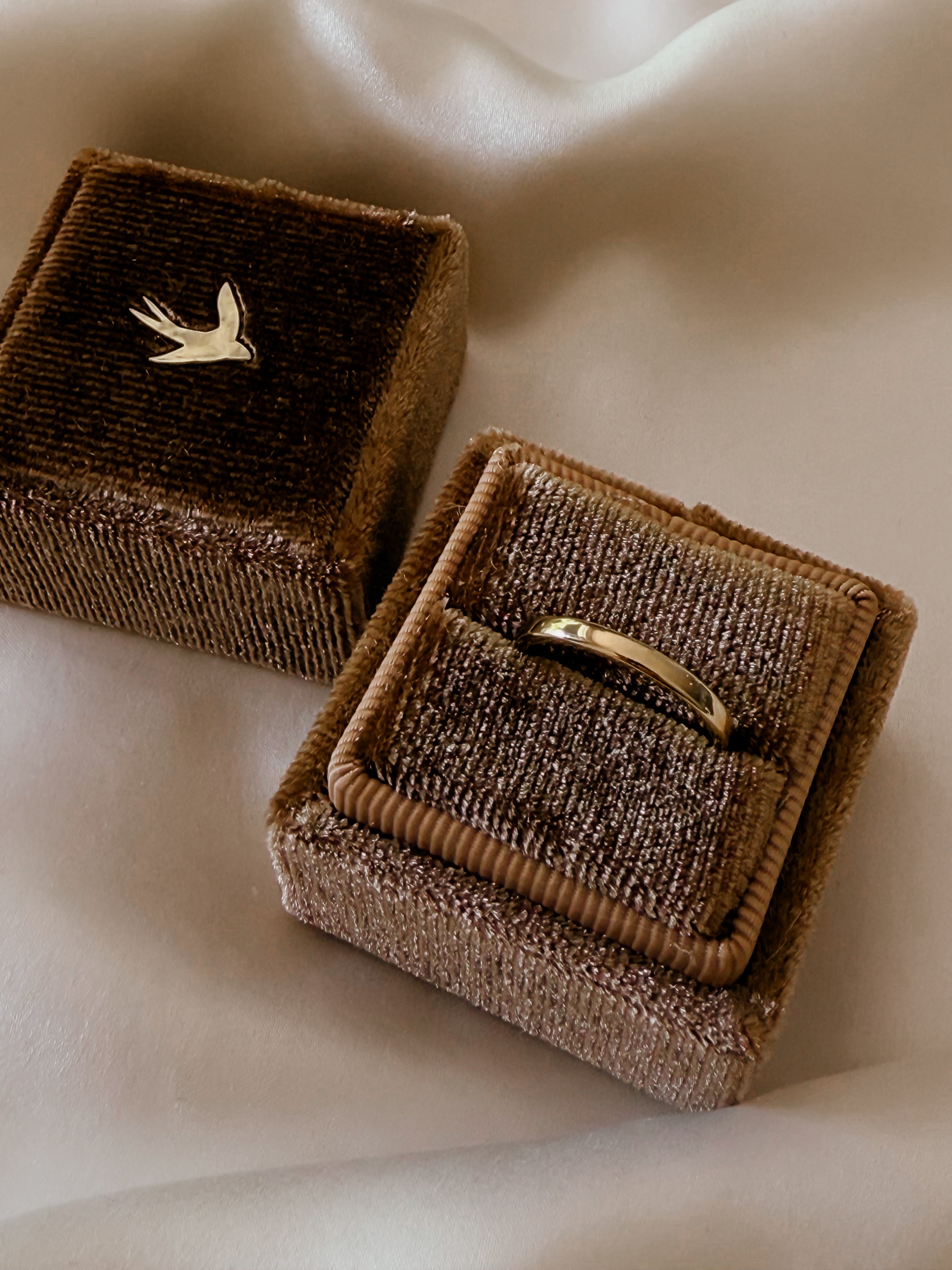 Adark brown velvet jewellery box holds a solid gold engraved band