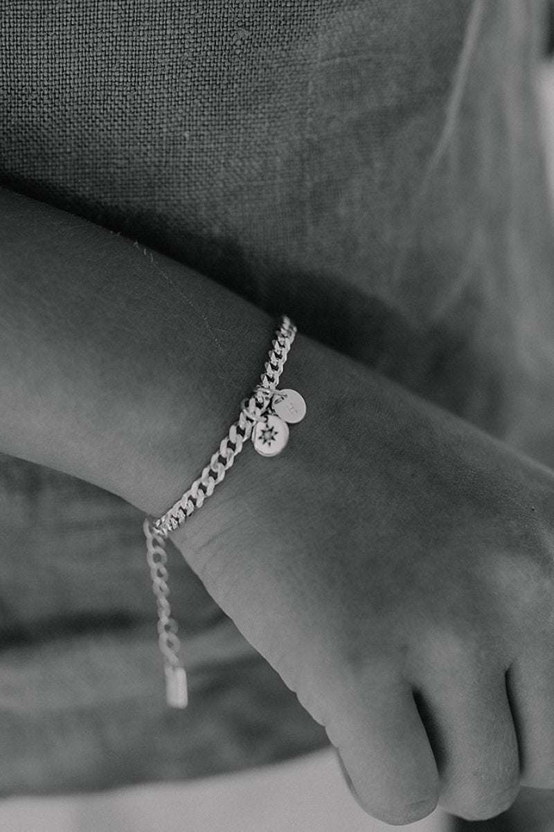 A child wearing a Cuban Link Chain with a single vintage pearl pendant with a personalised solid gold initial pendant, crafted in elegant fine jewellery
