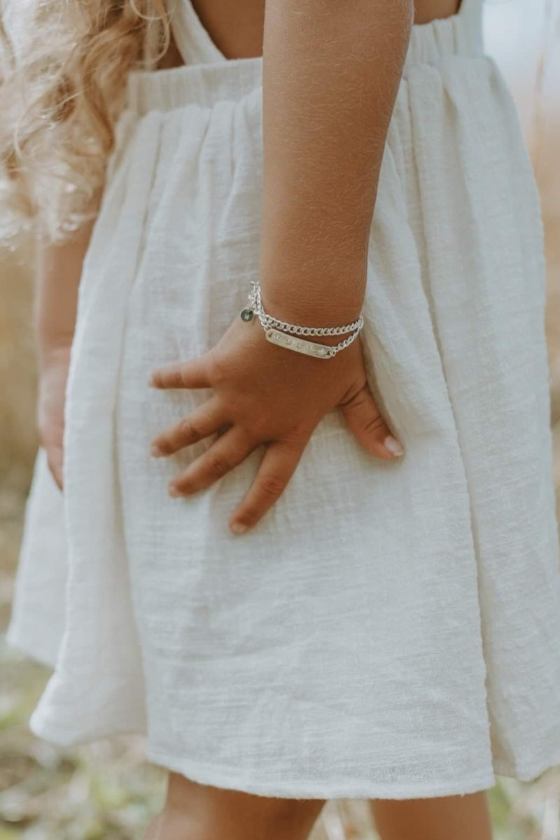 A detailed image of a young child wearing a Cuban Link Chain Necklace with a vintage pearl pendant and matching pearl bracelet, designed as a timeless keepsake.
