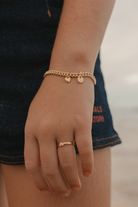 A detailed image capturing a young child wearing a Cuban Link Chain Bracelet with heart charm and initial pendant and matching signet ring, designed as timeless  jewellery pieces.