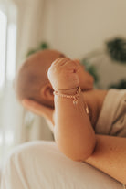 A close up image of a baby wrist wearing a Sweetheart Cuban Link Chain and polished heart pendant, designed as a timeless keepsake piece.
