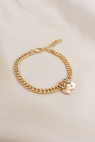 A gold chain bracelet with delicate heart charm and solid gold initial pendant for everyday wear. 