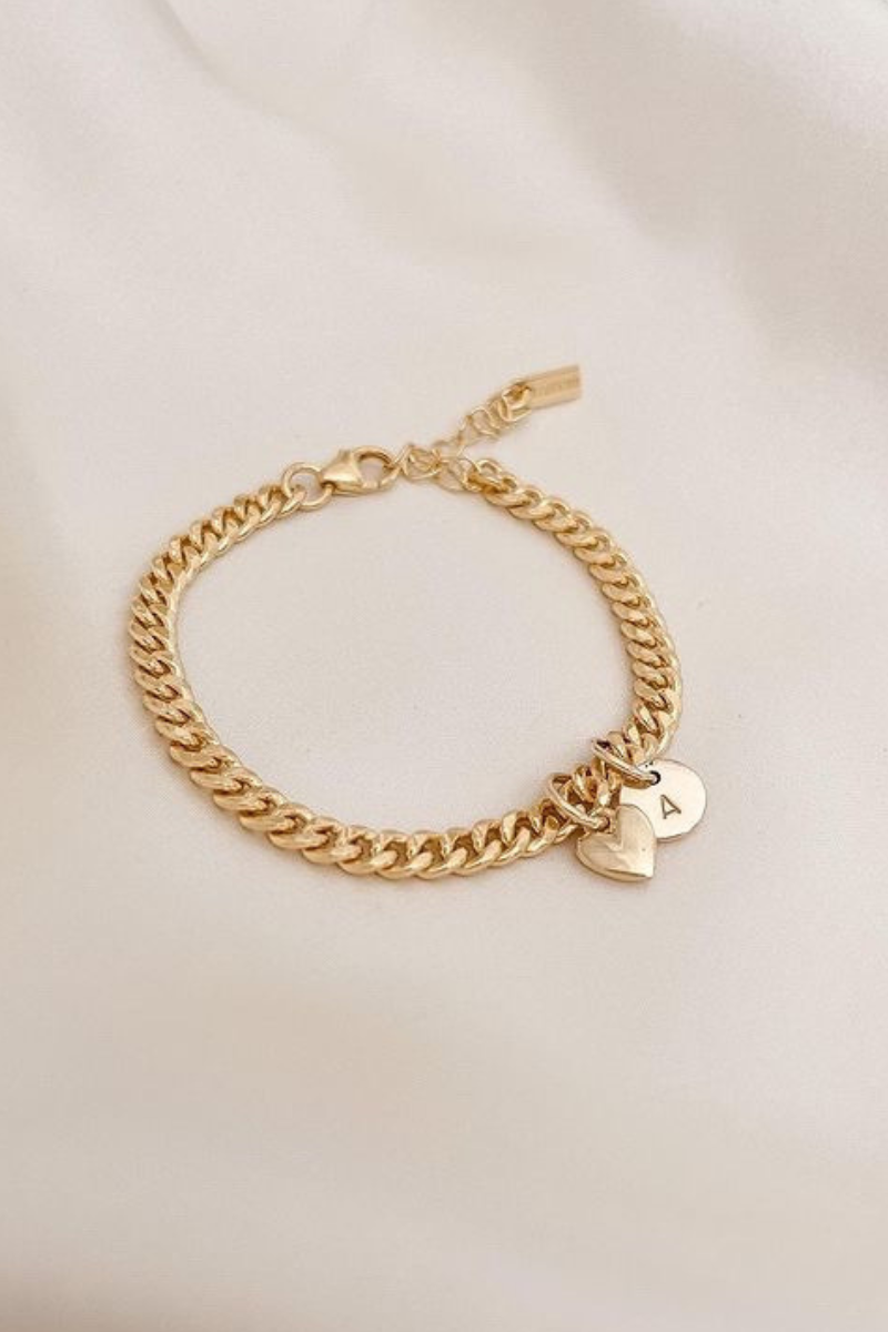 A gold chain bracelet with delicate heart charm and solid gold initial pendant for everyday wear. 