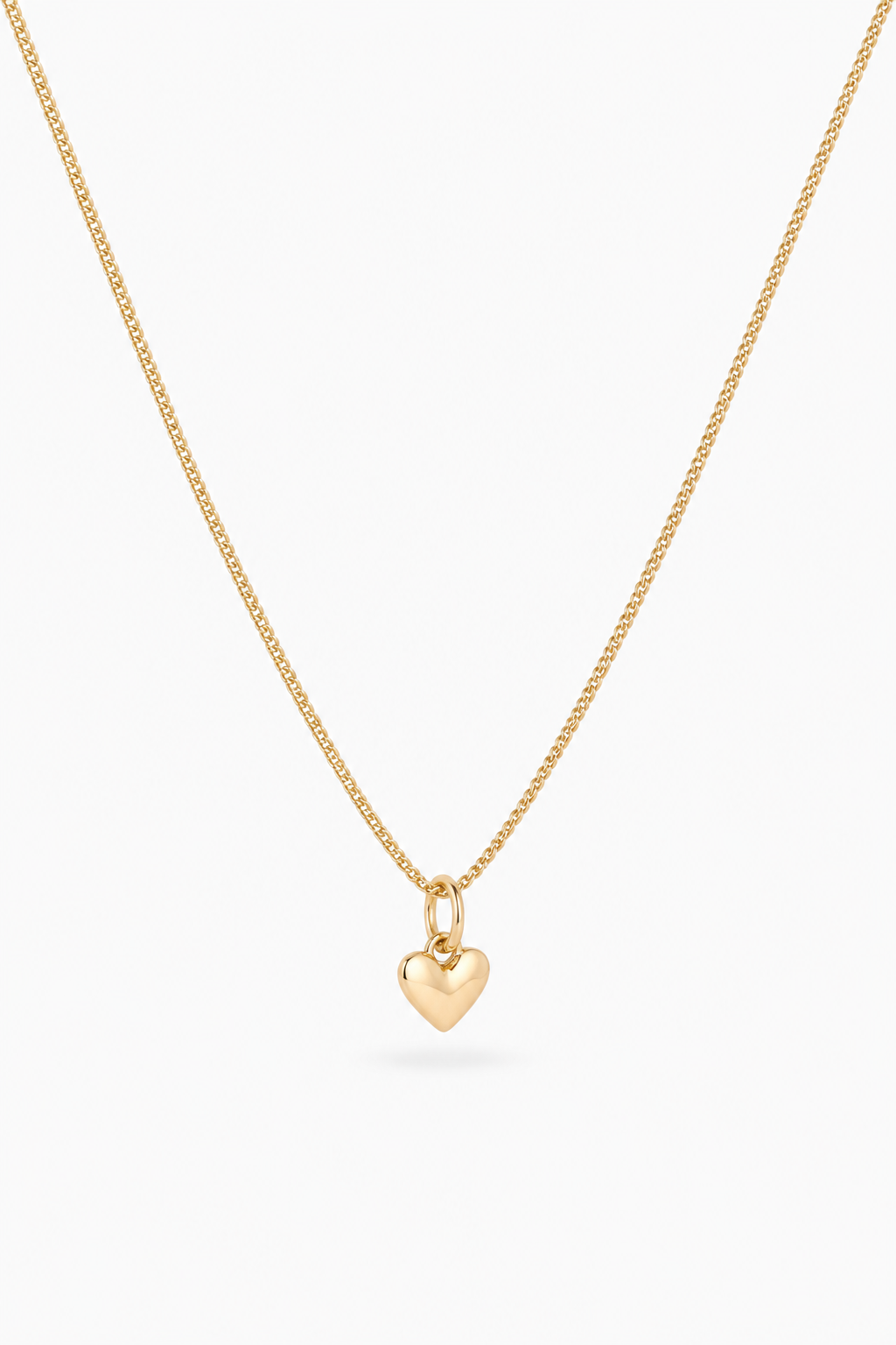 A delicate gold chain necklace with a small, polished gold heart pendant, displayed against a clean white background.