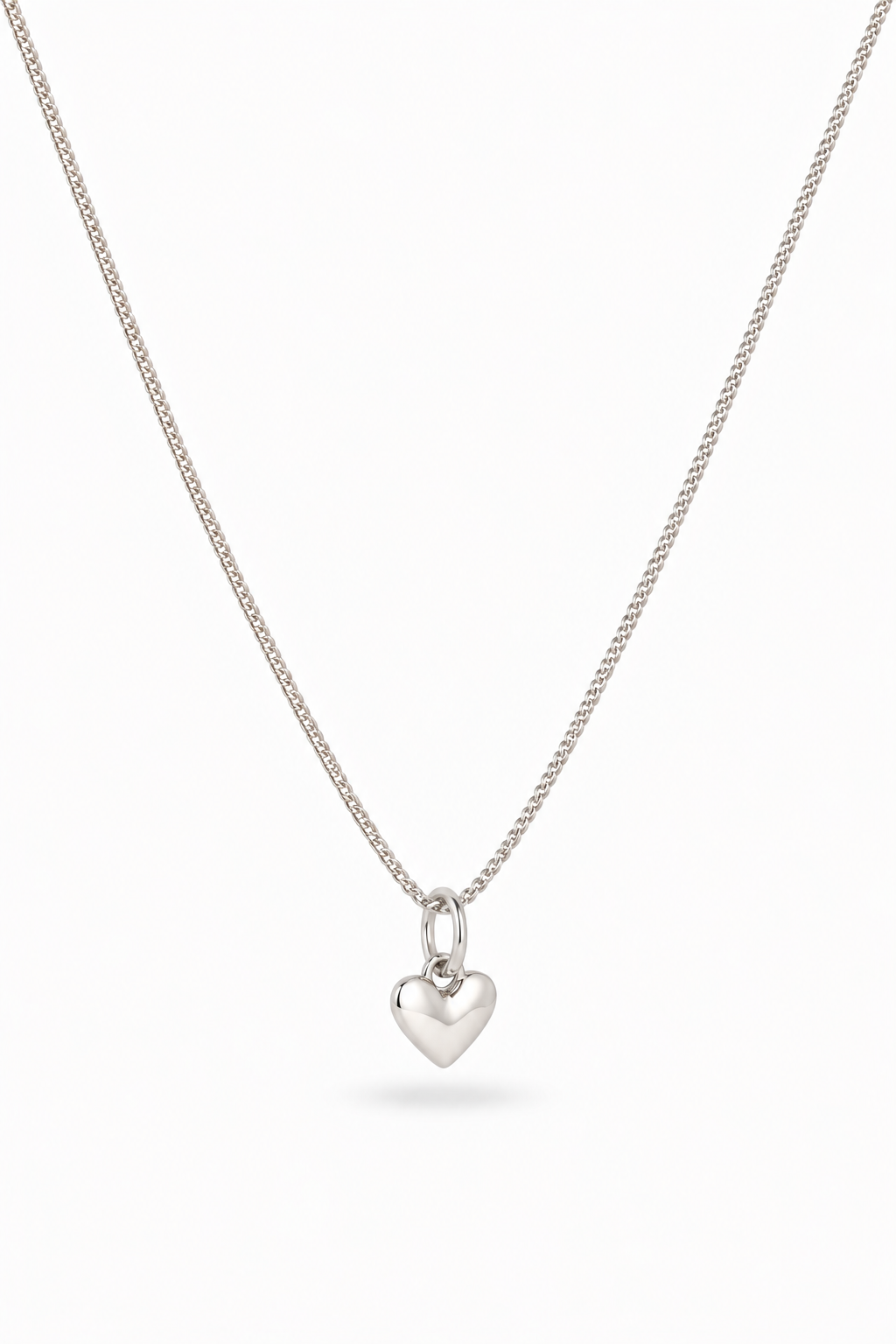 A delicate silver chain necklace with a small, polished heart-shaped pendant, displayed against a clean white background.
