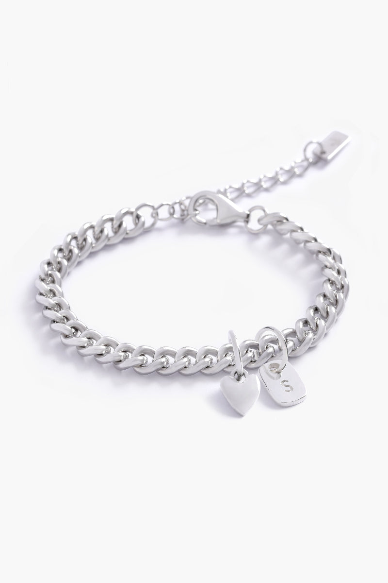 A detailed image of a silver Sweetheart Cuban Link Chain Bracelet with a heart charm and engraved initial pendant, designed as elegant personalised jewellery by Bluebird Co