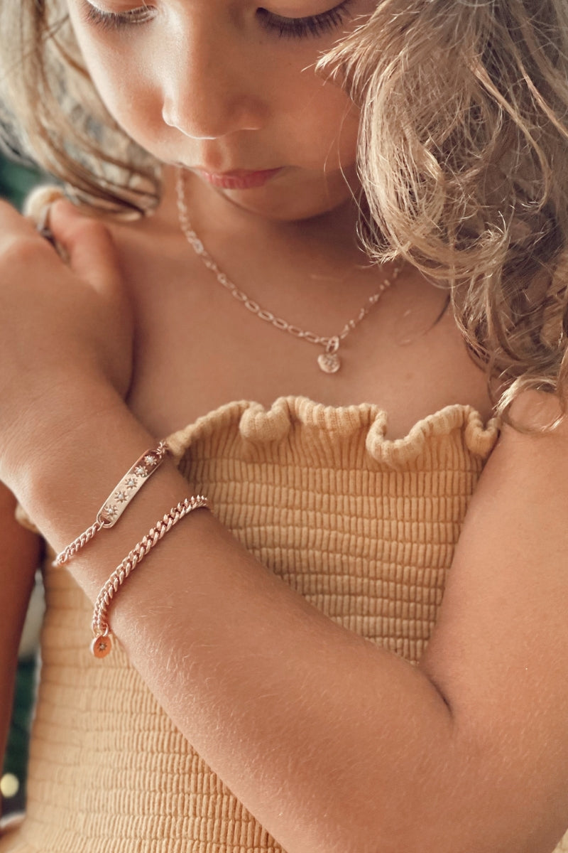 A close-up image of a child wearing the Darling Heart Bracelet by Bluebird Jewellery, showcasing five petite heart details within a refined and timeless gold chain.