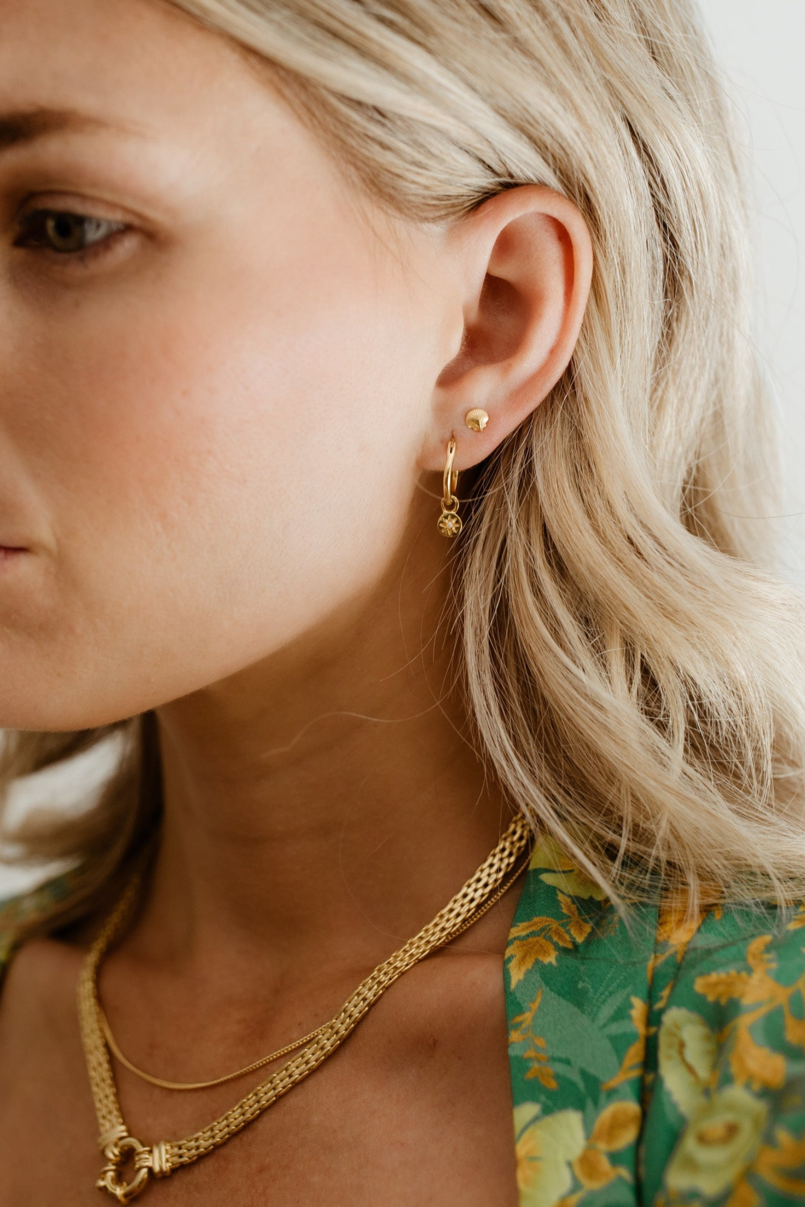 Petite Vintage Pearl Hoop is worn on the lower part of a woman's earlobe with the Petite Shell Stud sitting above it in her second earring hole in her earlobe.  The two earrings, whilst different, pair together with similar petite features and matching gold vermeil colour.