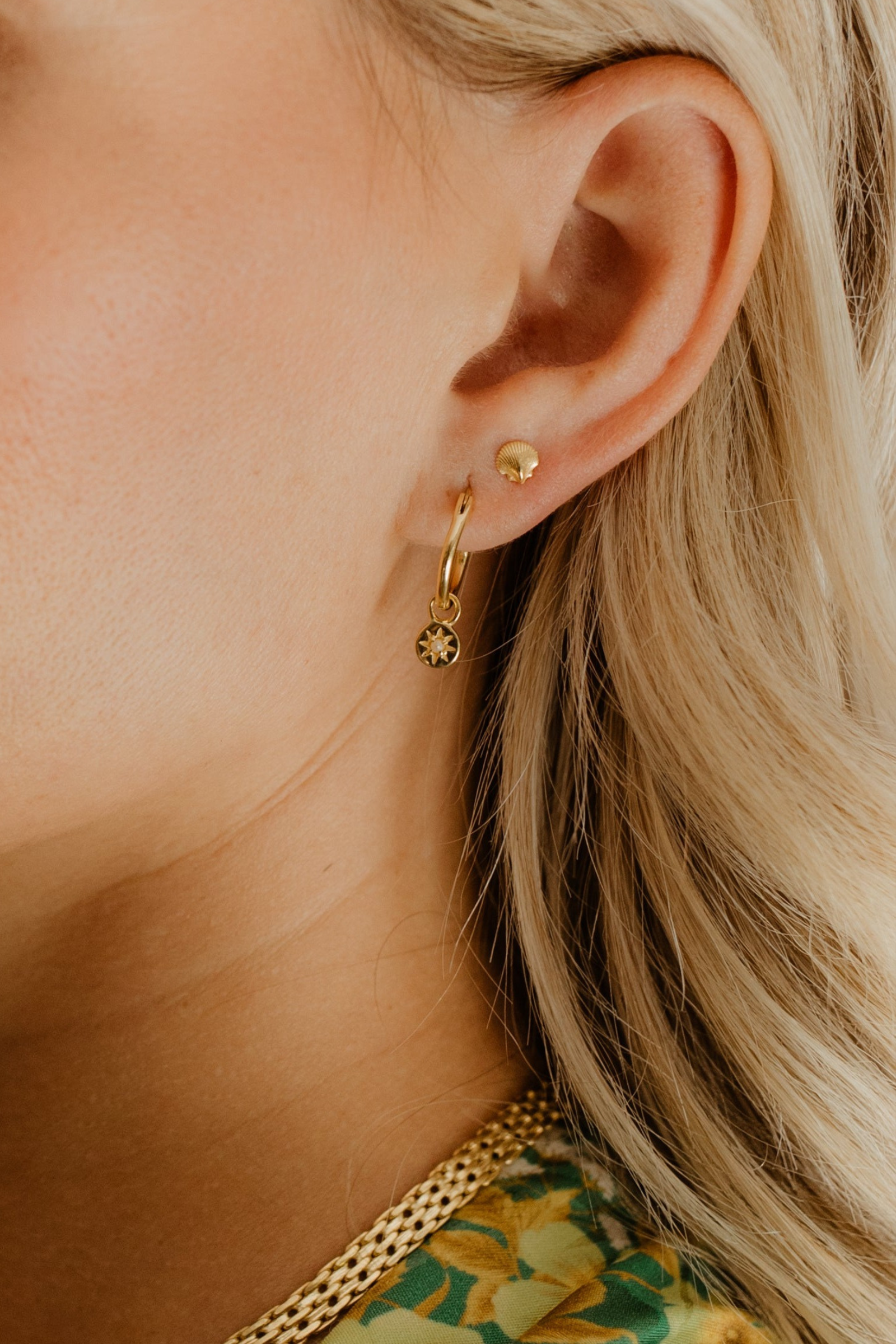 Petite Vintage Pearl Hoop is worn on the lower part of a woman's earlobe with the Petite Shell Stud sitting above it in her second earring hole in her earlobe.  The two earrings, whilst different, pair together with similar petite features and matching gold vermeil colour.
