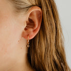 The Petite Vintage Pearl Hoop in Rose Gold Vermeil is being worn by a 10 year old girl.  The petite charm can slide on and off the hoop of the earring.