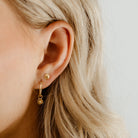 A Petite Shell Stud is worn with a Petite Vintage Pearl Earring in a woman's earlobe.