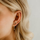 A Petite Vintage Pearl Stud sits next to a Petite Vintage Pearl Earring on a woman's earlobe.  The round surface with the seed pearl and vintage shaped star matches the charm on the hoop earring.