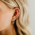 A Petite Vintage Pearl Hoop is worn alongside a Petite Daisy Hoop and two smaller studs are worn higher on the earlobe.