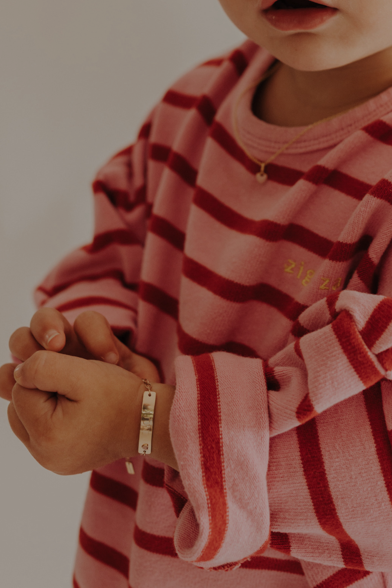Toddler wearing 9ct solid gold Pink Darling Bracelet with heart detail. Bluebird Jewellery.