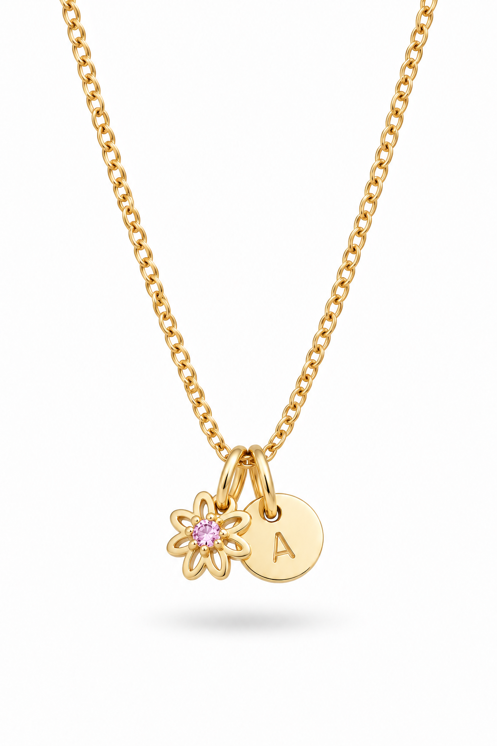 A gold chain necklace featuring a small gold flower charm with a pink gemstone and a round gold initial 'A' disc charm, shown on a clean white background.