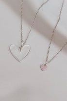 Silver heart pendant necklace paired with petite pink darling heart necklace. 