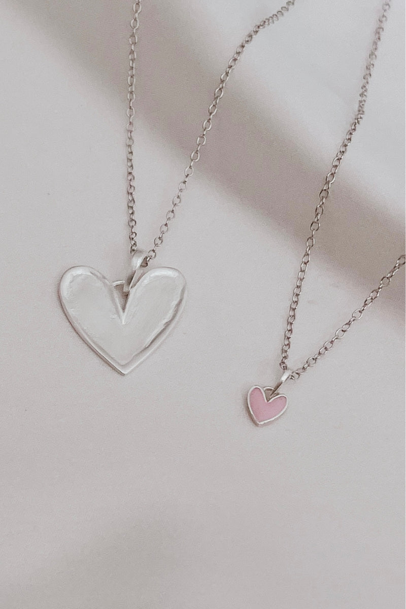 Silver heart pendant necklace paired with petite pink darling heart necklace. 