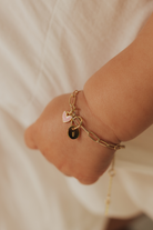 Baby and adult wearing Darling Posie Bracelets Gold with engraved charms, a meaningful family keepsake gift