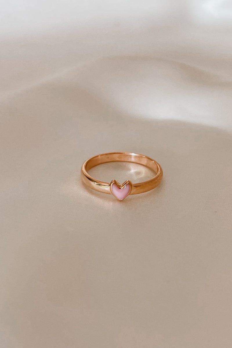 Closeup of a rose gold ring with pink heart detail.