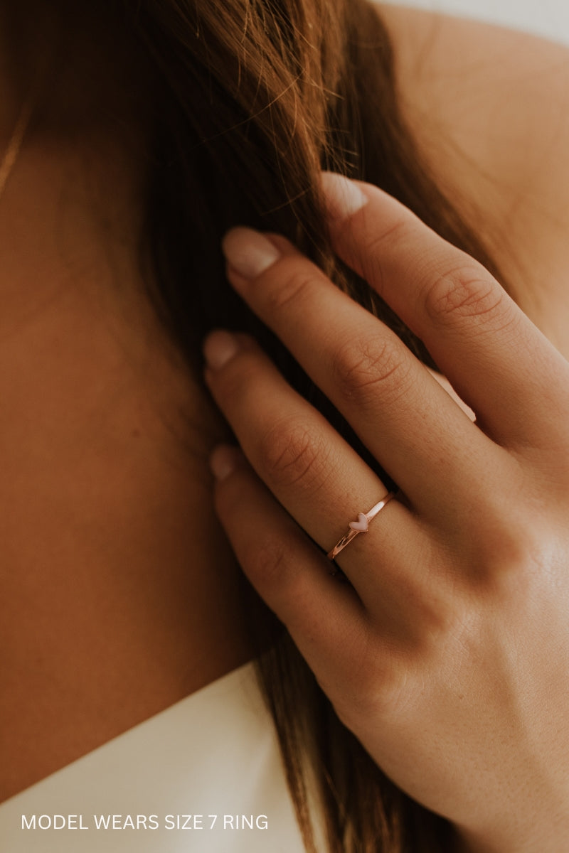 Rose gold heart ring worn on hand, showing dainty fit and shine. 