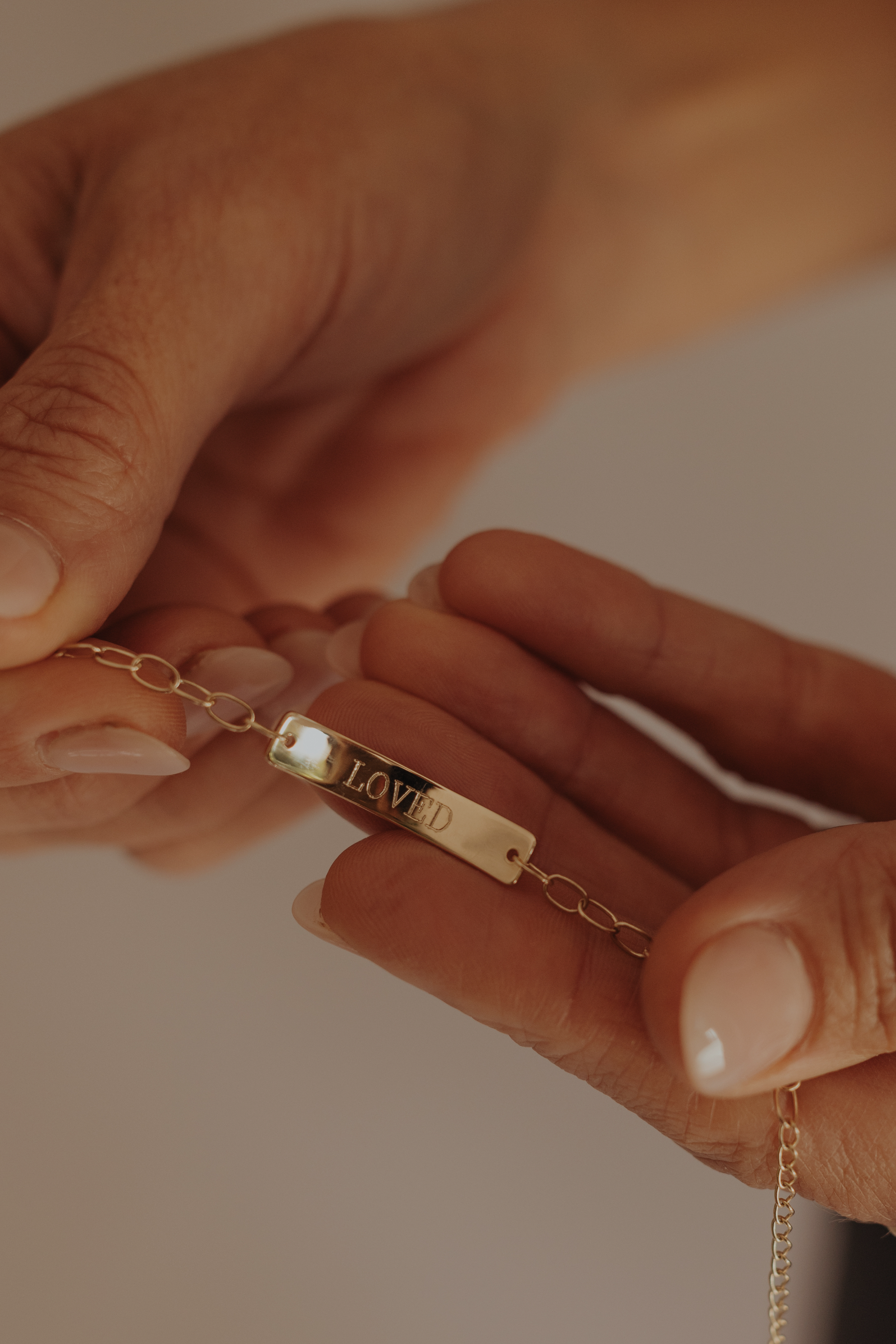olid gold Pink Darling Bracelet engraved with "LOVED", captured in warm natural light