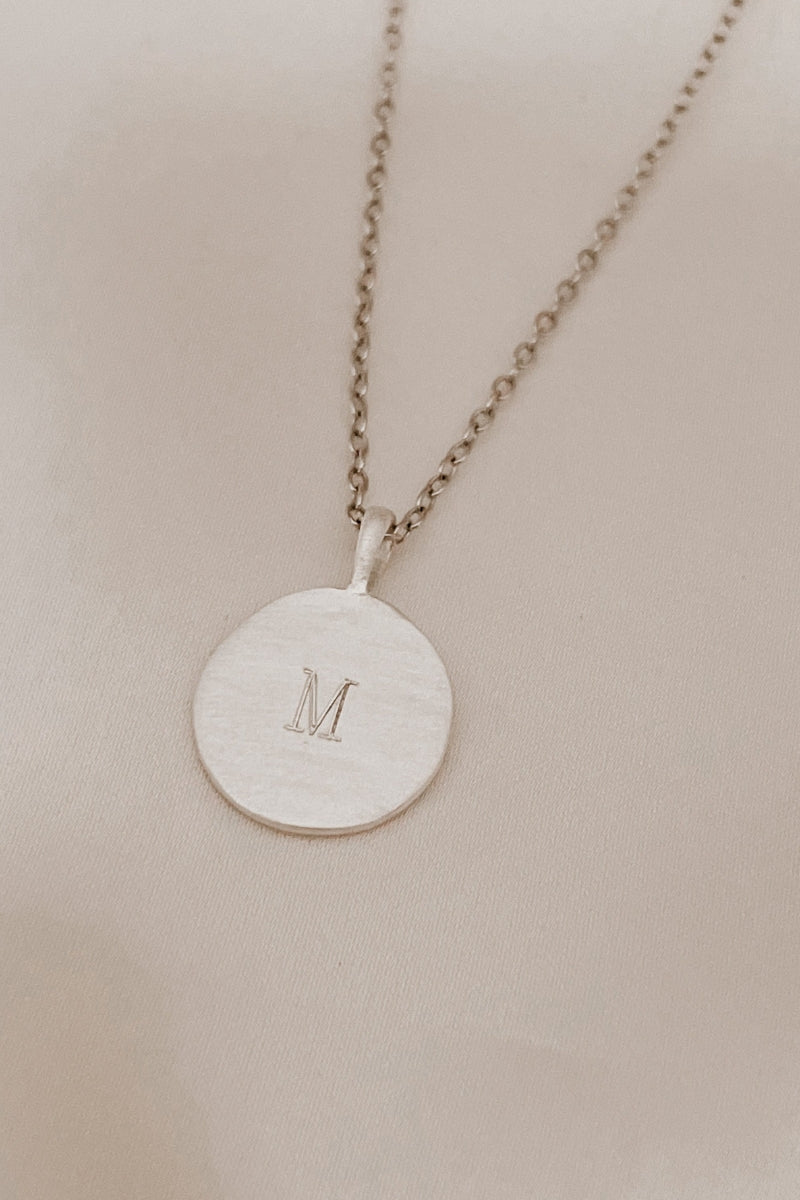 Petite signature necklace in silver with engraved M, styled for children or mums who love minimal classics.