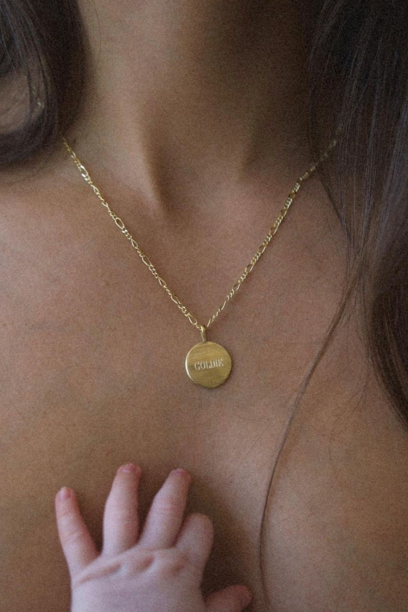 A mother is wearing the 45+5cm Signature Necklace with the name 'Goldie' engraved on the front of the pendant.