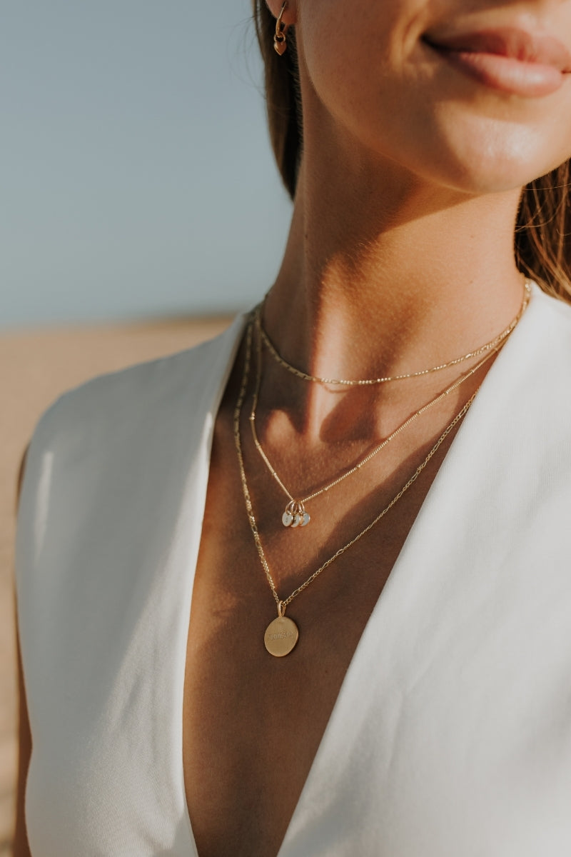 Signature Gold Necklace layered with other chains, styled at the beach for elegant, everyday wear.