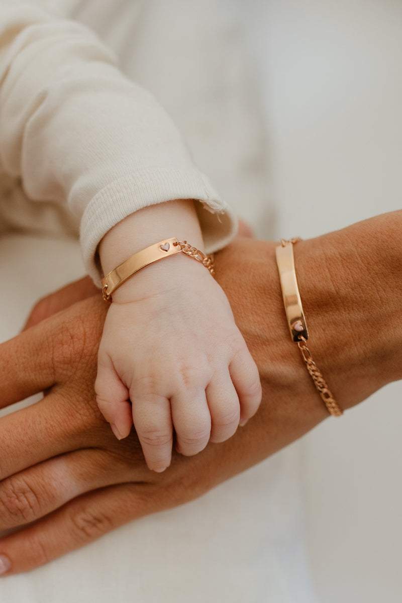 Baby and parent wearing matching Pink Darling Rose Gold bracelets—engraved jewellery to celebrate love, family, and milestones.