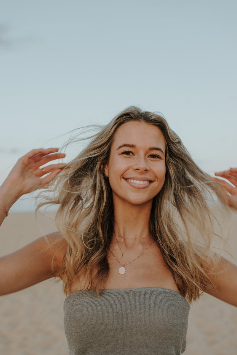 Close-up of woman smiling while wearing personalised rose gold disc necklace
