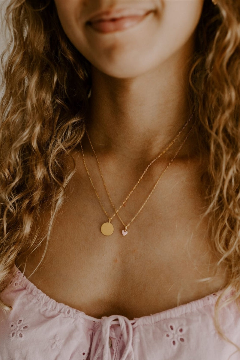 Young woman wearing engraved petite gold pendant necklace with personalised text.