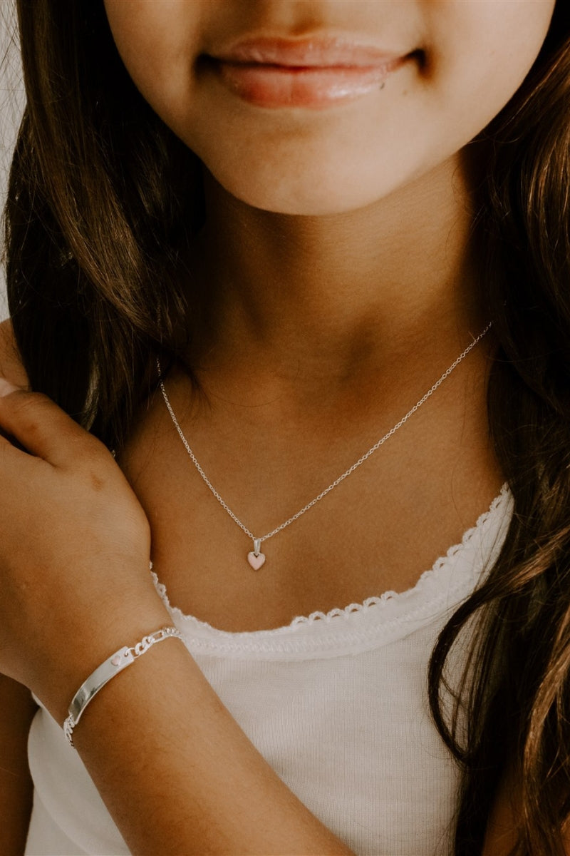 Girl wearing pink heart necklace and matching engraved silver bracelet