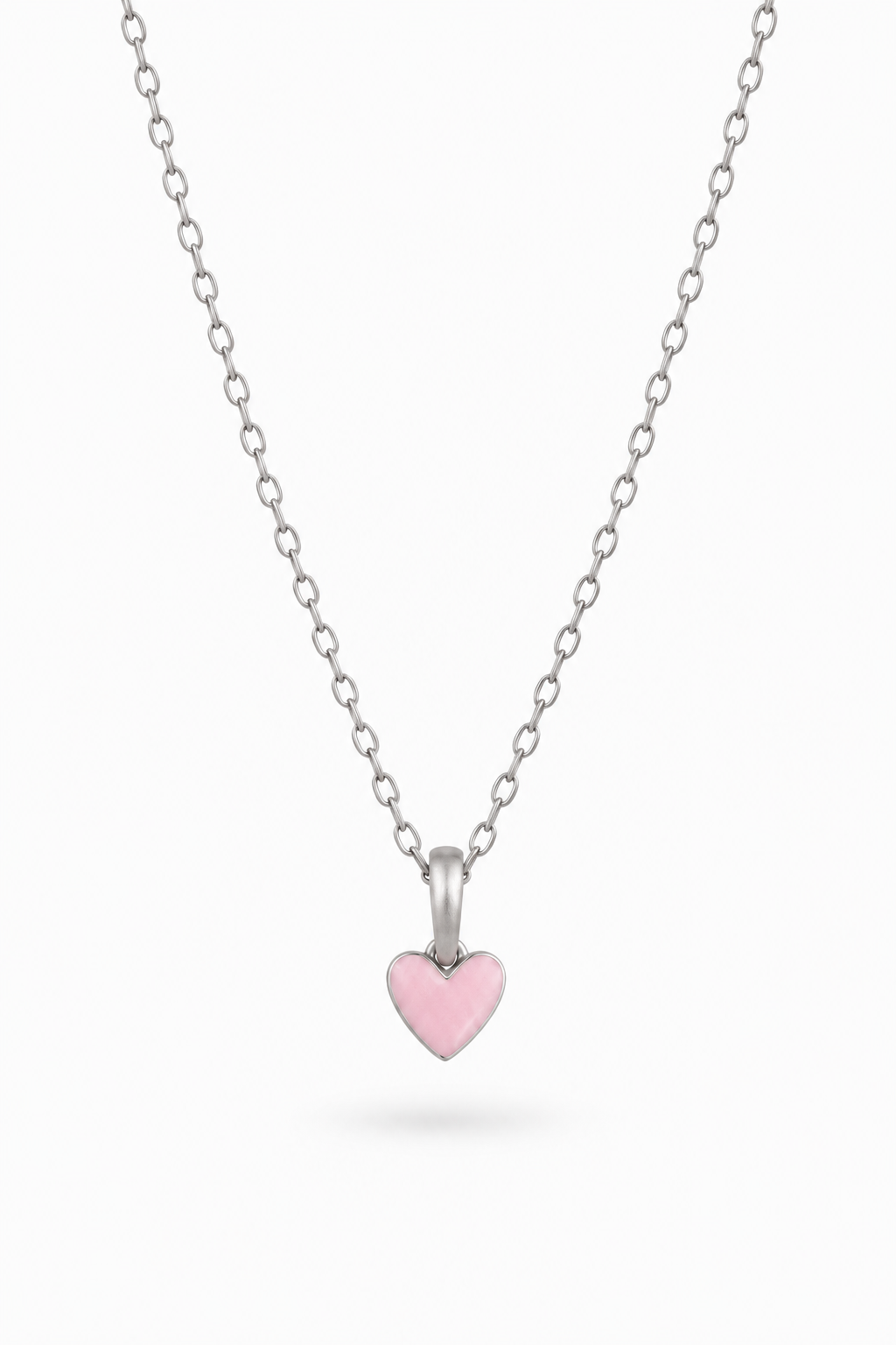 A delicate silver chain necklace featuring a small, polished silver heart pendant with a smooth, light pink enamel center, displayed against a clean white background.
